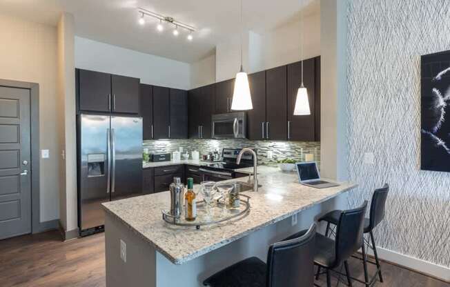A modern kitchen with a granite countertop and stainless steel appliances.