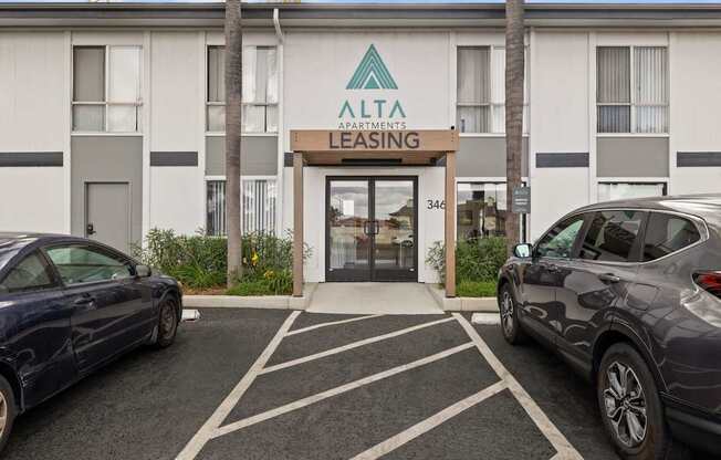 A blue car is parked in front of a building with a sign that reads