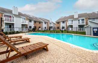 a swimming pool with two wooden benches next to an apartment building