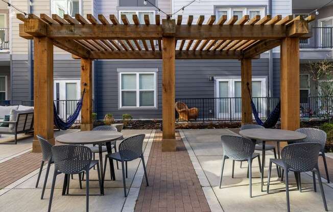 a patio with tables and chairs and a wooden pergola
