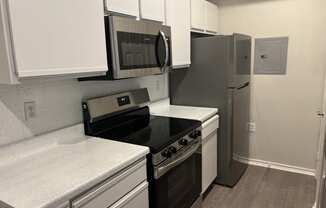 a kitchen with white cabinets and black appliances and a refrigerator