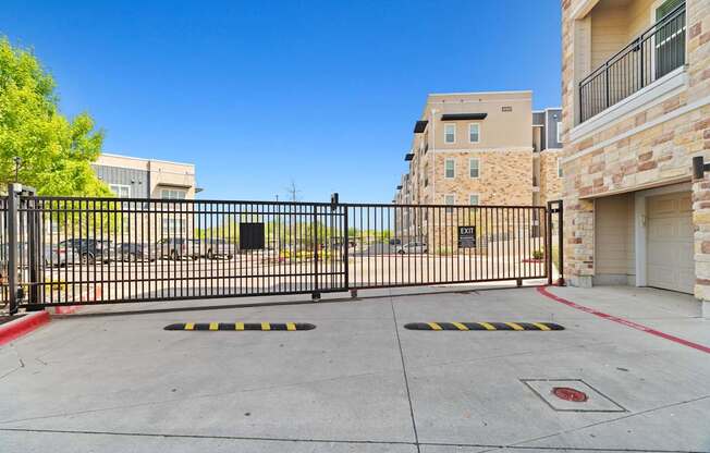 A black gate blocks the entrance to a driveway.