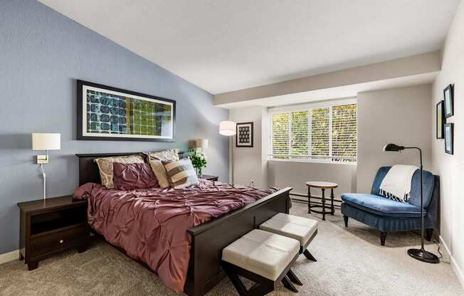 A bedroom with a bed, chair, and window.