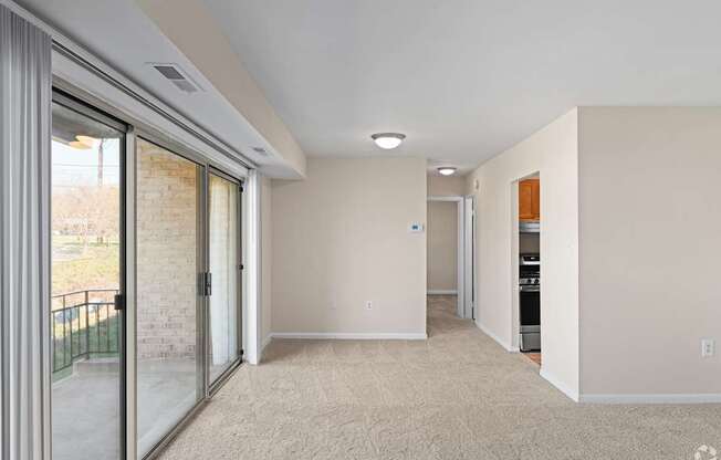 A spacious room with a sliding glass door leading to a balcony.