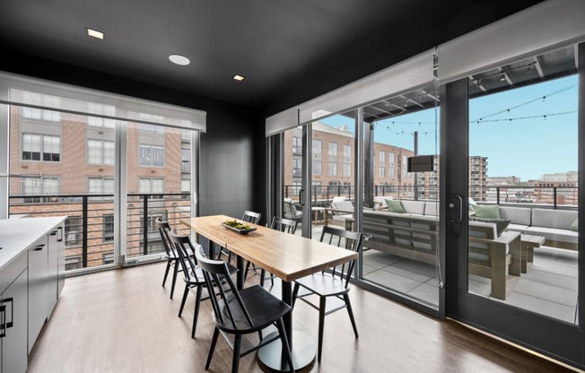 a dining area with a wooden table and chairs and a large window with a balcony