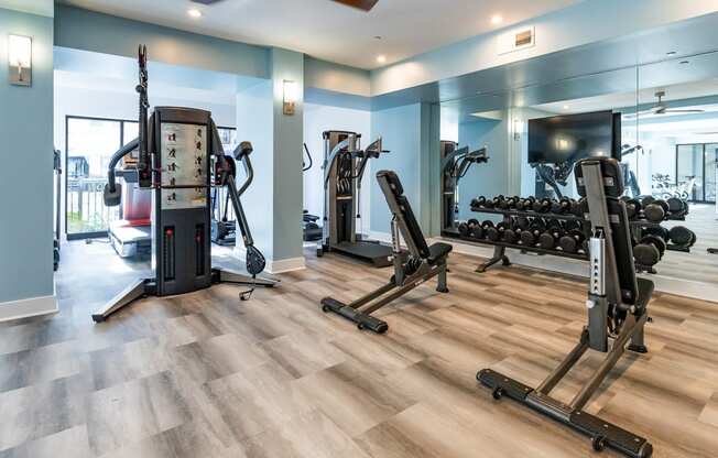 a gym with exercise machines and weights on a wooden floor