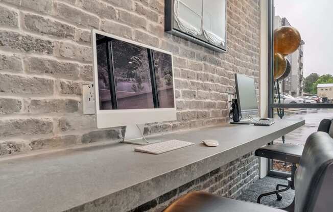 a desk with a computer on it against a brick wall