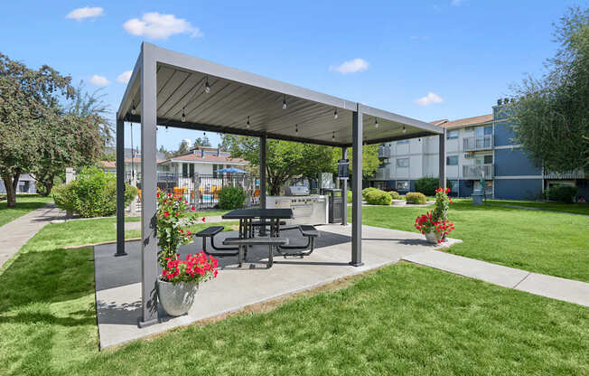 A picnic area with a table and chairs under a canopy.