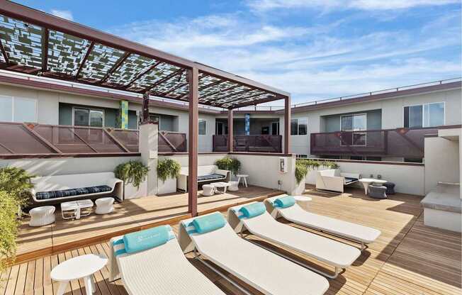 A sunny day at the rooftop patio with white lounge chairs and blue cushions.