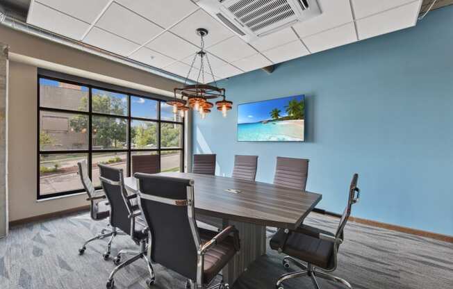 a conference room with a table and chairs and a tv on the wall