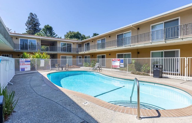 a swimming pool in front of a building with a resort style pool