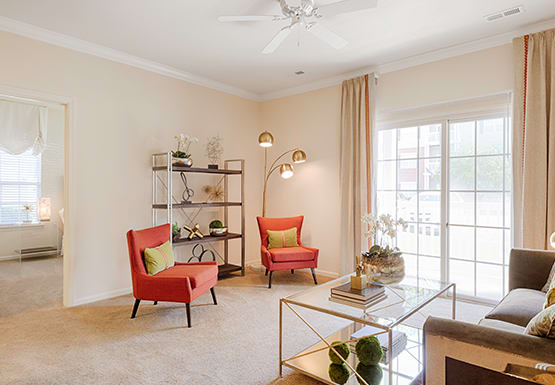 Living room with couch and chair; door to patio or balcony; door to bedroom