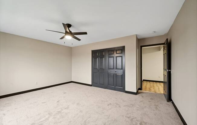 an empty living room with a ceiling fan and a door