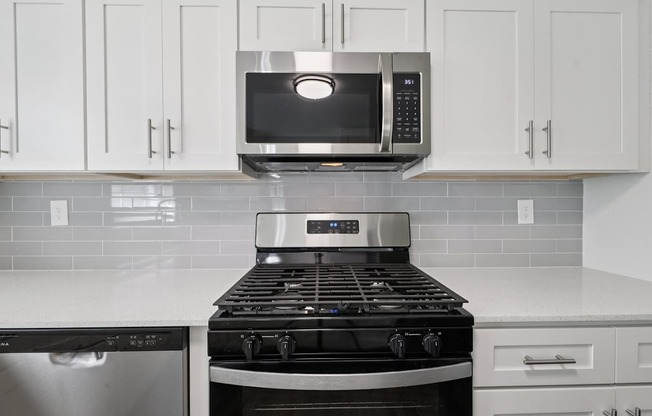 A modern kitchen with a stove top oven and microwave above it.