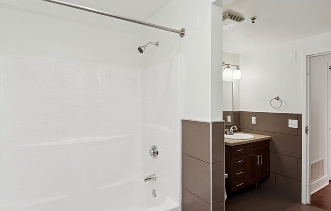 A white tiled bathroom with a sink and mirror.