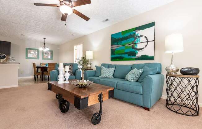 A living room with a blue couch and a painting on the wall.