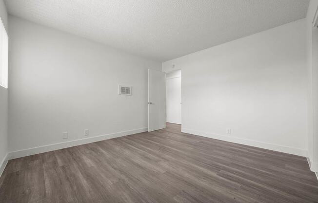 A room with wooden flooring and white walls.