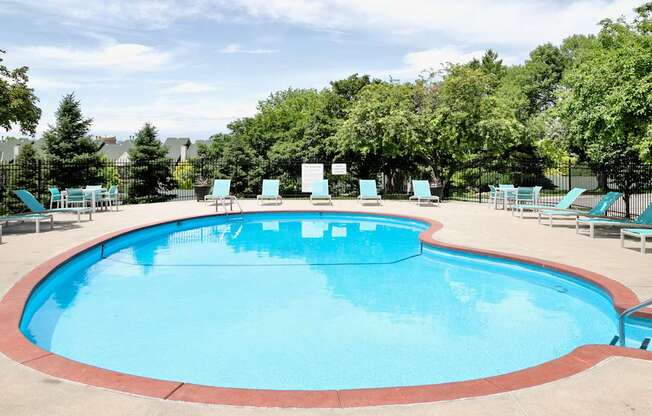 A large outdoor swimming pool surrounded by trees and lounge chairs.