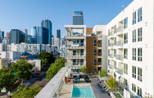 an aerial view of an apartment complex with a swimming pool and a city skyline in the background