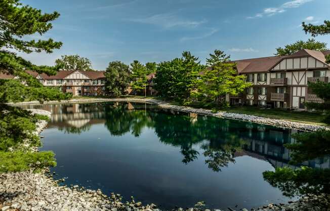 a large pond in front of a building with trees