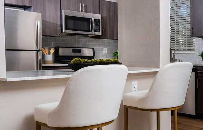 a kitchen with two white chairs in front of a counter