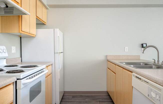 A kitchen with a white stove and white refrigerator with wooden cabinets.
