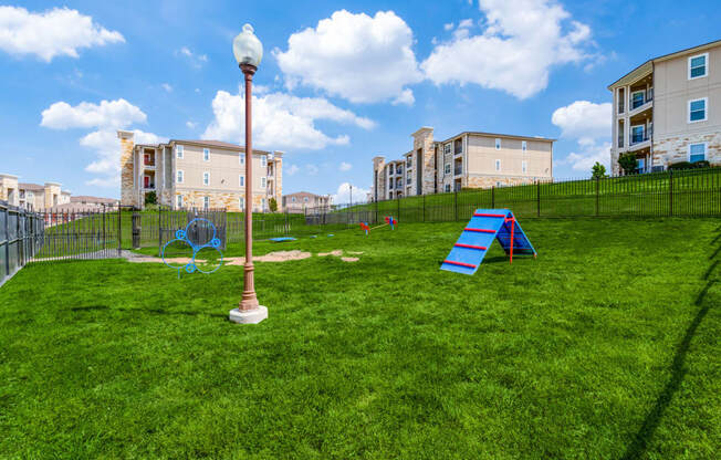 a playground on the grass with apartments in the background