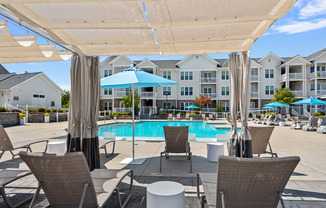 a swimming pool with chairs and umbrellas in front of an apartment building