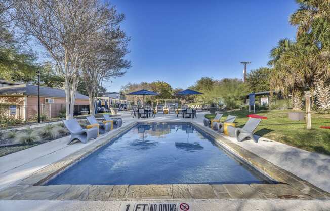a swimming pool with chairs around it and a patio with umbrellas  at Sunset Ridge, Texas