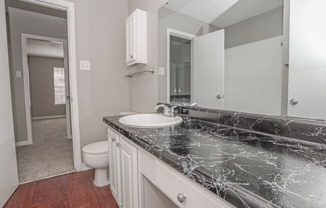 A bathroom with a marble vinyl countertop and a white sink at Magnolia apartments in Shreveport, LA
