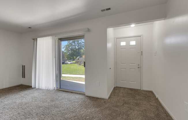 a living room with white walls and a door to a backyard