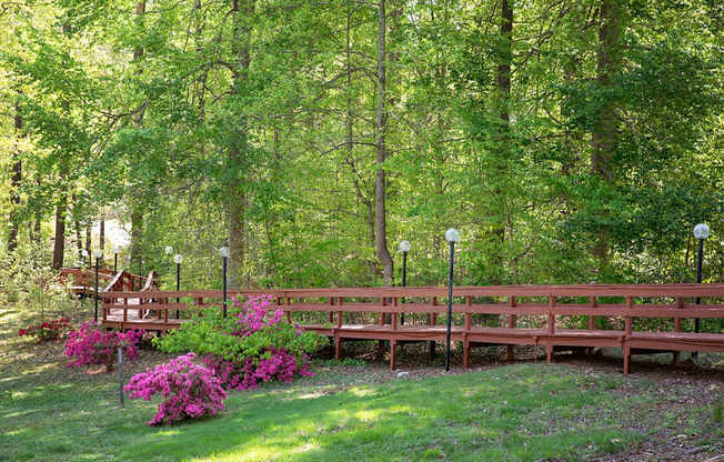 A wooden bench is surrounded by trees and flowers.