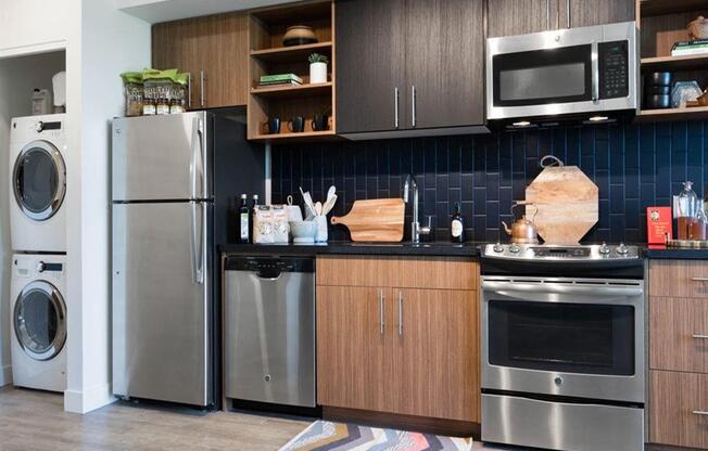 Kitchen with stainless steel appliances and blue subway tile backsplash at Cook Street Apartments, Portland