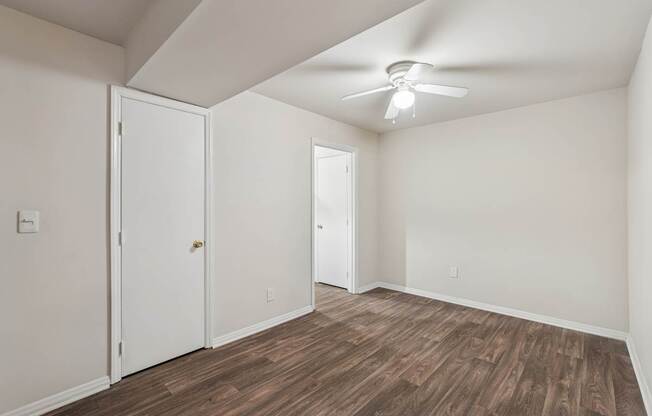 A room with a ceiling fan and wood flooring.