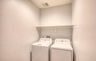 Two white washing machines in a small laundry room.