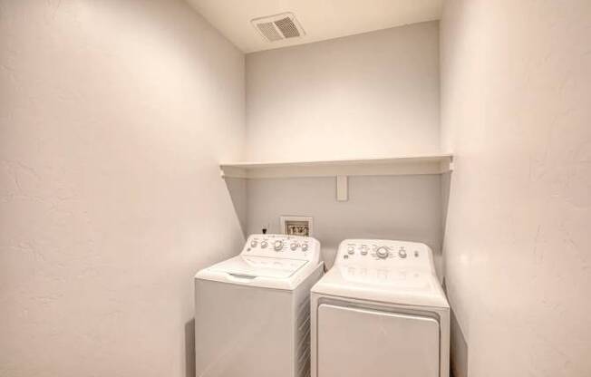 Two white washing machines in a small laundry room.