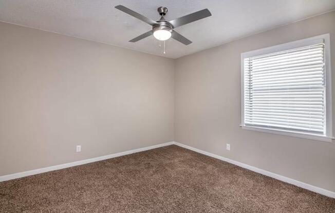 an empty bedroom with a ceiling fan and a window at Cleo Apartments, Athens, 35611