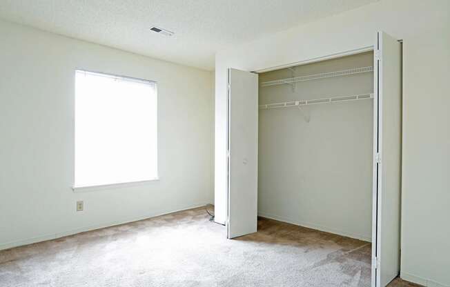 an empty room with a closet and a window