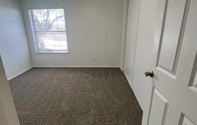 an empty room with a carpeted floor and a window