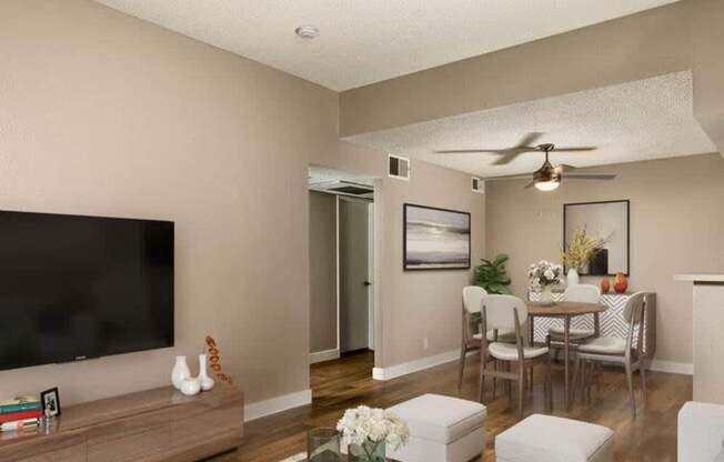 A living room with a flat screen TV, a coffee table, and a dining table with chairs.