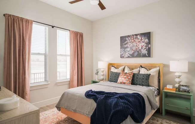 A bedroom with a bed, nightstand, and window with curtains.