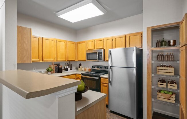 A kitchen with wooden cabinets and a stainless steel refrigerator. at Somerset Oaks Apartment Homes, Olathe