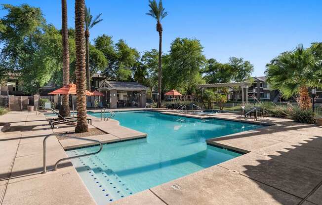 A pool surrounded by palm trees and a building in the background.