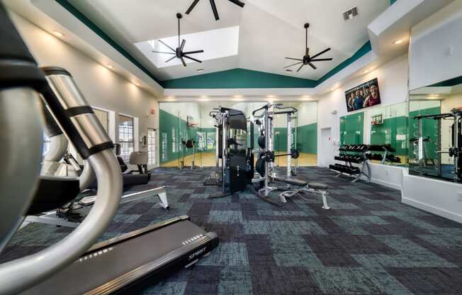a gym with weights and cardio equipment in a building with green walls