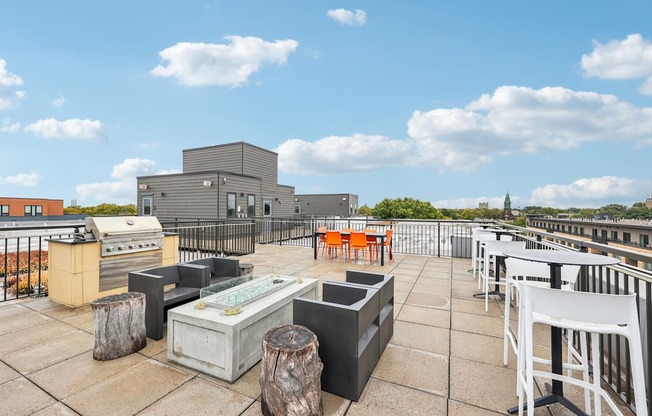 A rooftop patio with white chairs and a bar area.