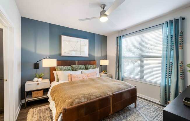 a bedroom with blue walls and a large window and a bed