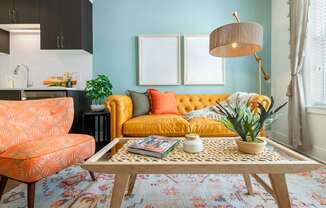 A living room with a yellow sofa, a patterned rug, and a wooden coffee table.