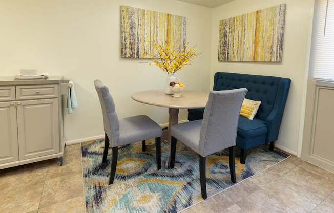 A dining room with a round table and grey chairs.