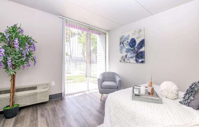 A room with a bed, a chair, and a plant.