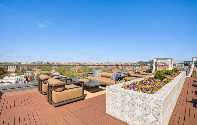 A rooftop patio with a white planter box and brown furniture.